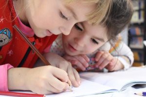 Two little girls reading book together